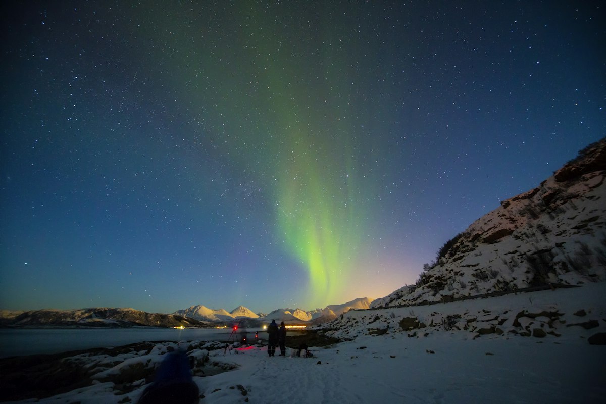 Two travellers beneath the Northern Lights near Tromsø, Norway